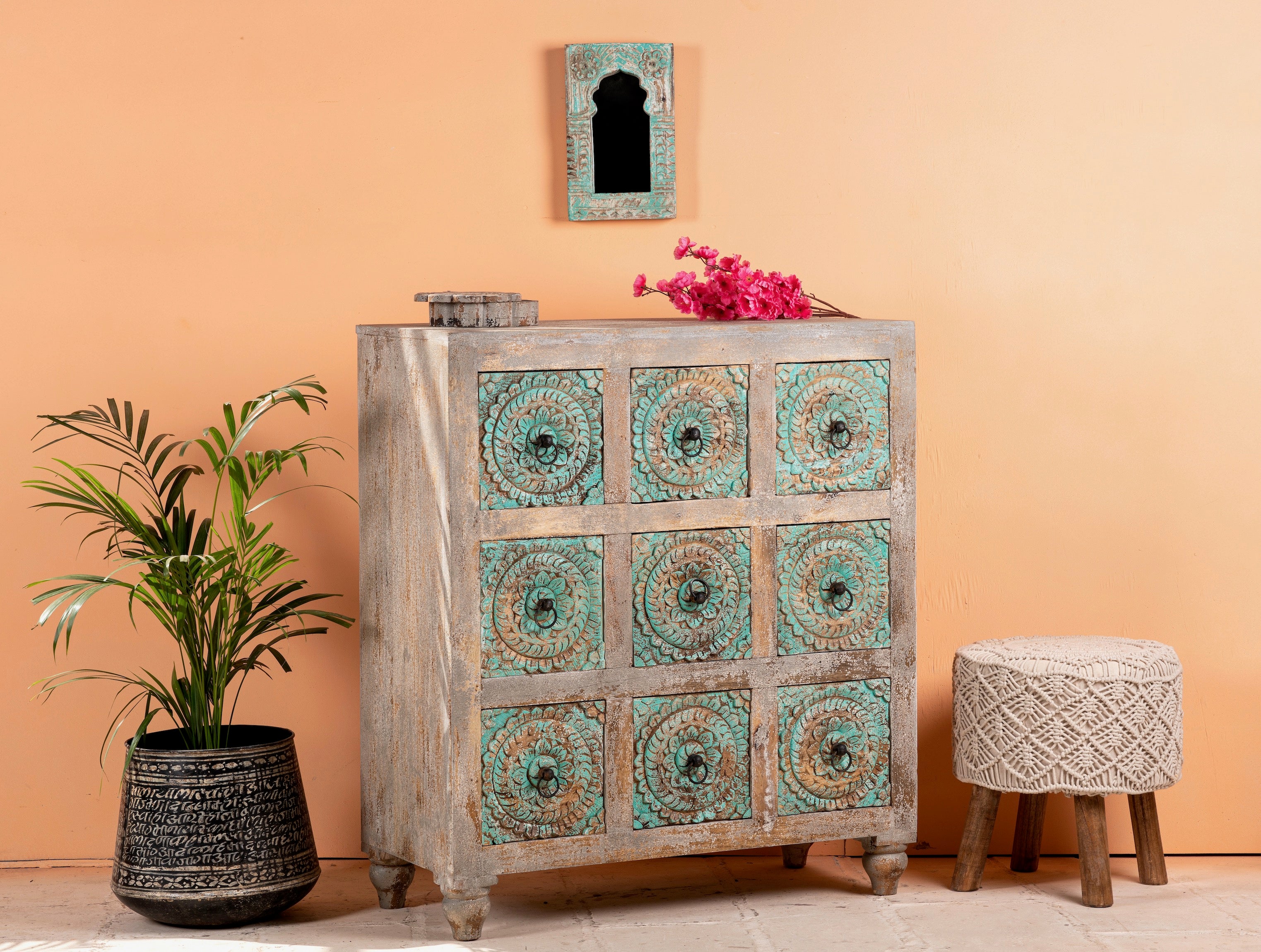 Side angle image of a hand-carved mango wood vintage chest of drawers with greenwashed floral fronts and antique white finish; perfect for bedroom furniture, 90 × 100 × 40 cm.