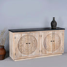 Side view of an acacia wood sideboard with 4 doors and iron fitted door knobs with floral round carvings and a black marble top.