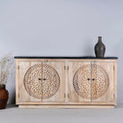 Front view of an acacia wood sideboard with 4 doors and iron fitted door knobs with floral round carvings and a black marble top.