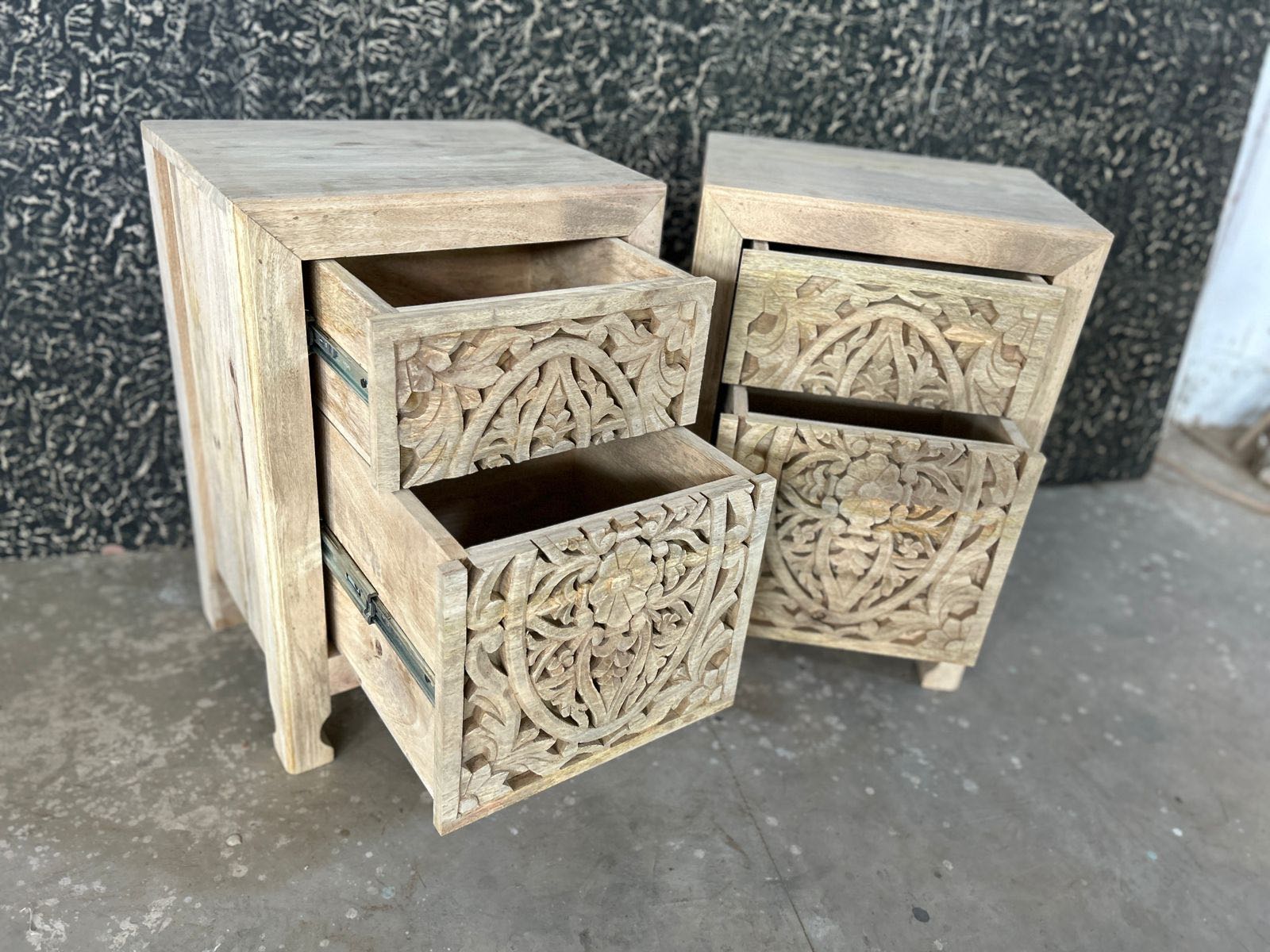 Side angle with open drawer of a air of hand-carved nightstands made of sandblasted mango wood with floral Mediterranean patterns and two drawers – Aanya bedside tables by Om Home & Garden