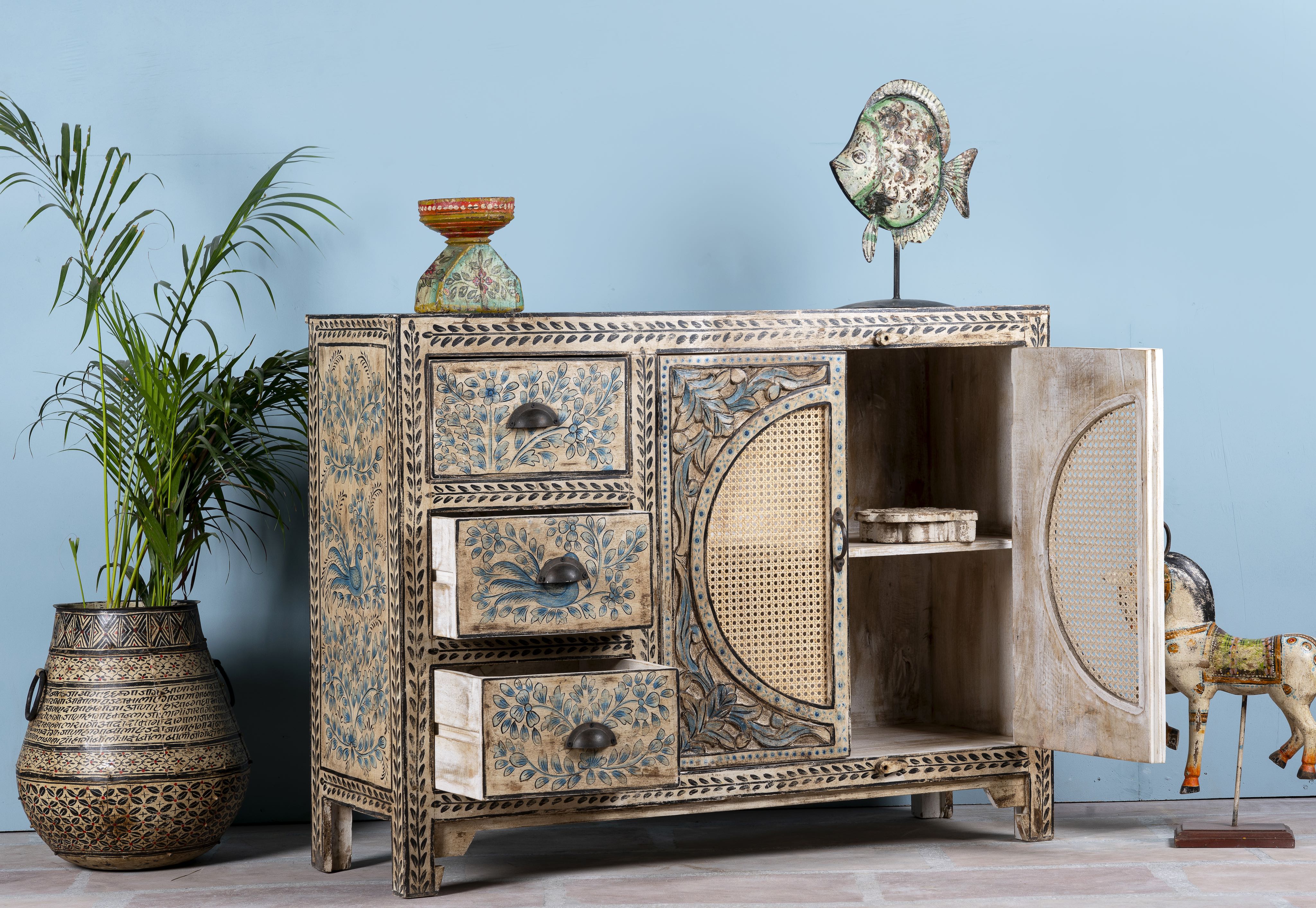 Open door image of a hand painted sideboard in blue and beige with rattan door inserts; unique furniture for boho style interiors, 120 × 40 × 92 cm.