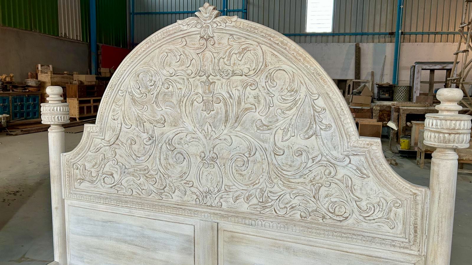Close up image of the head board of a handcrafted Indian bed in solid mango wood with carved headboard and footboard, rustic bedroom furniture, 160 × 200 cm.
