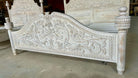 Carved wooden bed with intricate designs on a plain background
