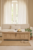 Lifestyle image of a Ibiza style carved mango wood chest with sandblasted finish and iron lock; 150 × 40 × 45 cm.