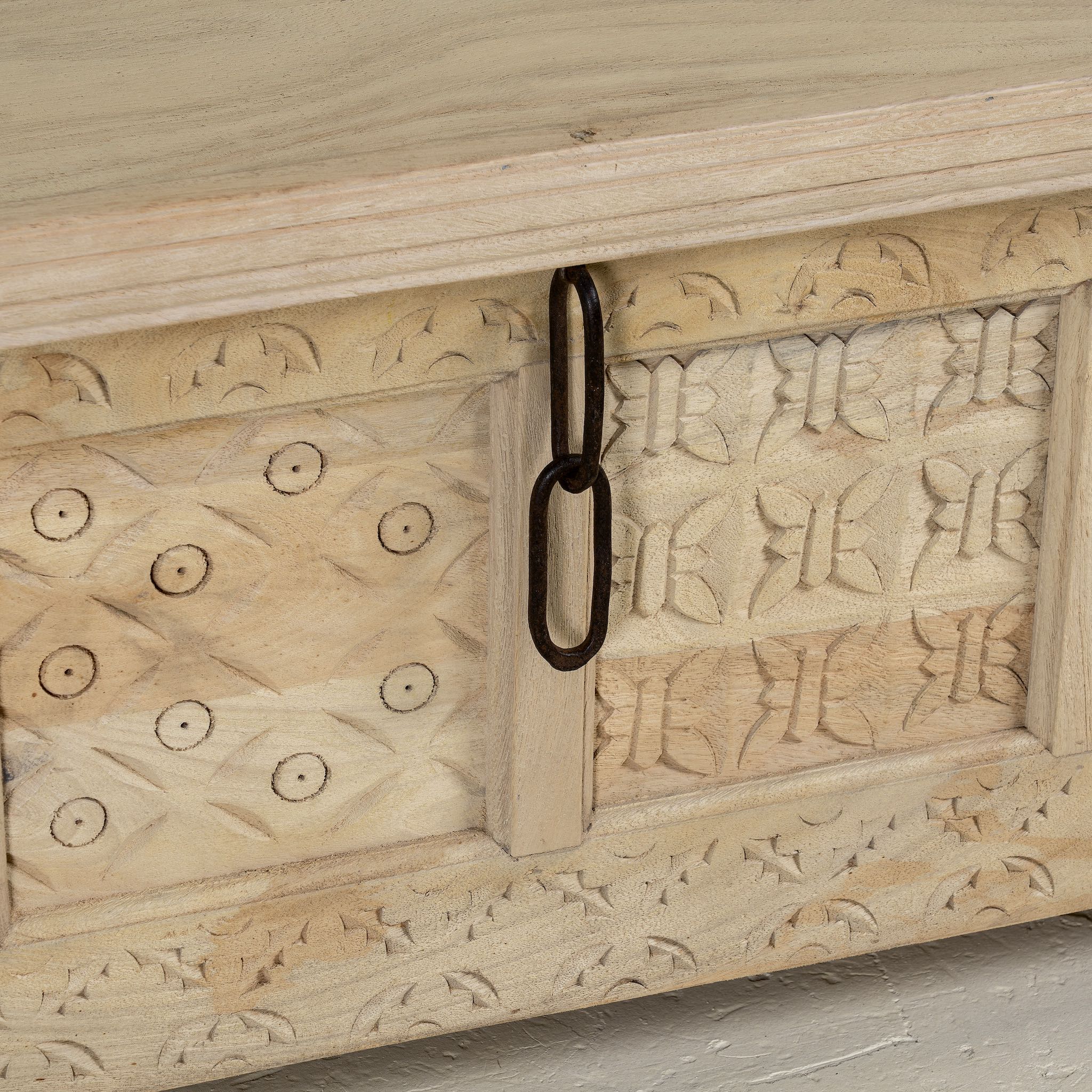 Close up image of a Ibiza style carved mango wood chest with sandblasted finish and iron lock; 150 × 40 × 45 cm.