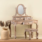 Side angle image of a handcrafted mango wood cosmetic table with a curved mirror and matching stool, showcasing a vintage style with a beige finish.
