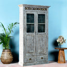 Side angle image of a reclaimed teak wood cabinet in shabby chic white with glass doors and ceramic inlays – dining room furniture with vintage elegance.