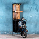 Side image of a high bar table featuring the front half of a vintage Bajaj scooter, with tall wooden shelving and an industrial metal frame, designed for stylish bar storage.