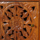 Close up image of a pair of hand-carved bedside tables made of mango wood, featuring intricate round floral hand carvings on the doors. 