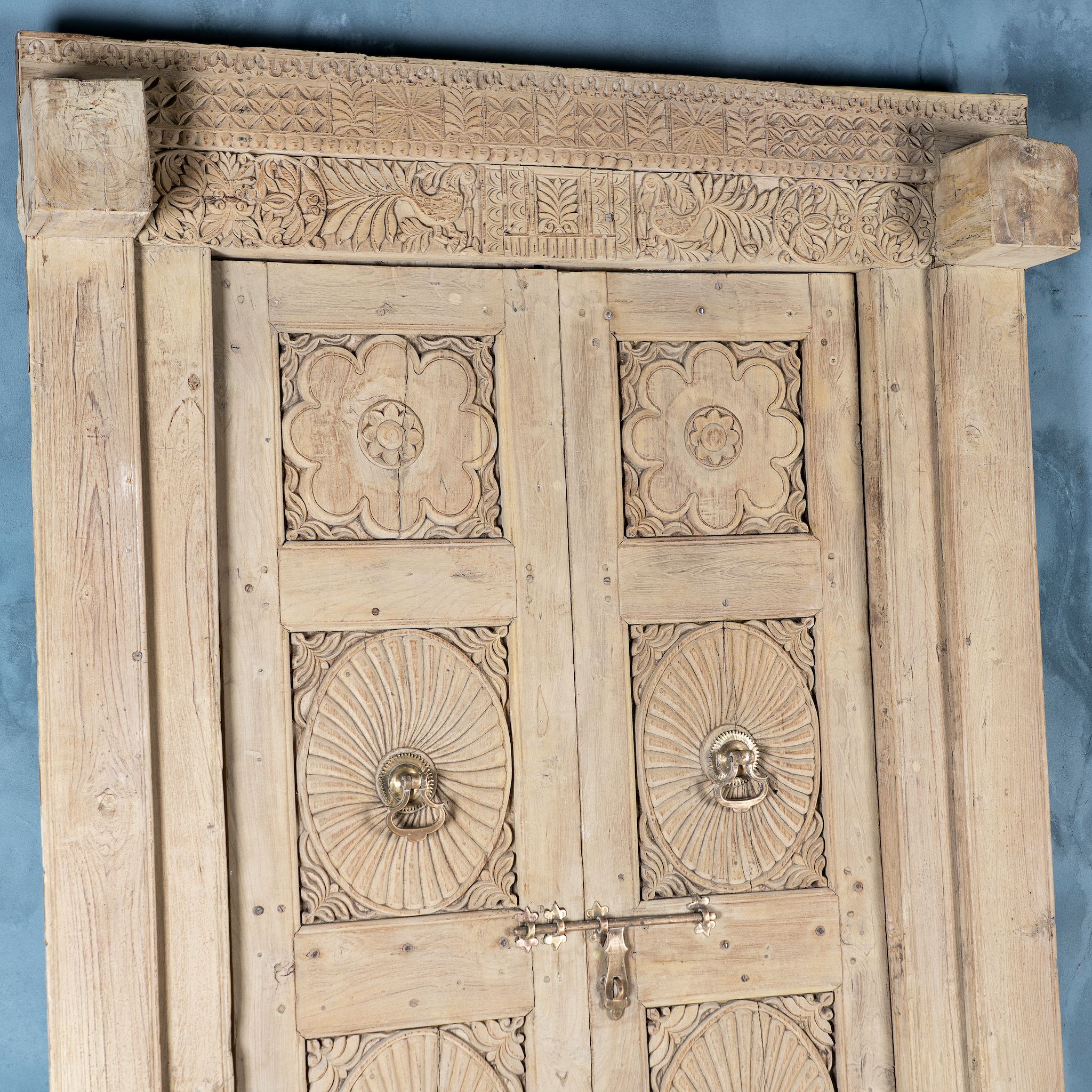 Close up image of a one-of-a-kind antique Indian teak door with sandblasted finish, original brass locks, and reclaimed wood frame extended to European height standards.