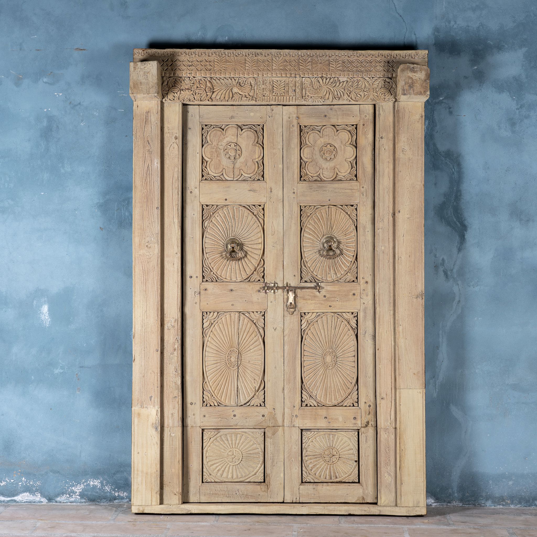One-of-a-kind antique Indian teak door with sandblasted finish, original brass locks, and reclaimed wood frame extended to European height standards.