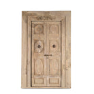 White background image of a heavy reclaimed Indian teak door with unique hand carvings, sandblasted finish, and original brass hardware, extended to fit European height within a restored frame.