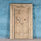 Heavy reclaimed Indian teak door with unique hand carvings, sandblasted finish, and original brass hardware, extended to fit European height within a restored frame.