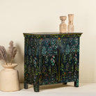 Side angle image of a hand painted cupboard made from recycled wood with floral motifs, two drawers and two doors, 90 × 90 × 40 cm.