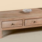 Close up image of a minimalistic wooden coffee table made from reclaimed wood with three drawers; natural finish, 150 × 60 × 45 cm.