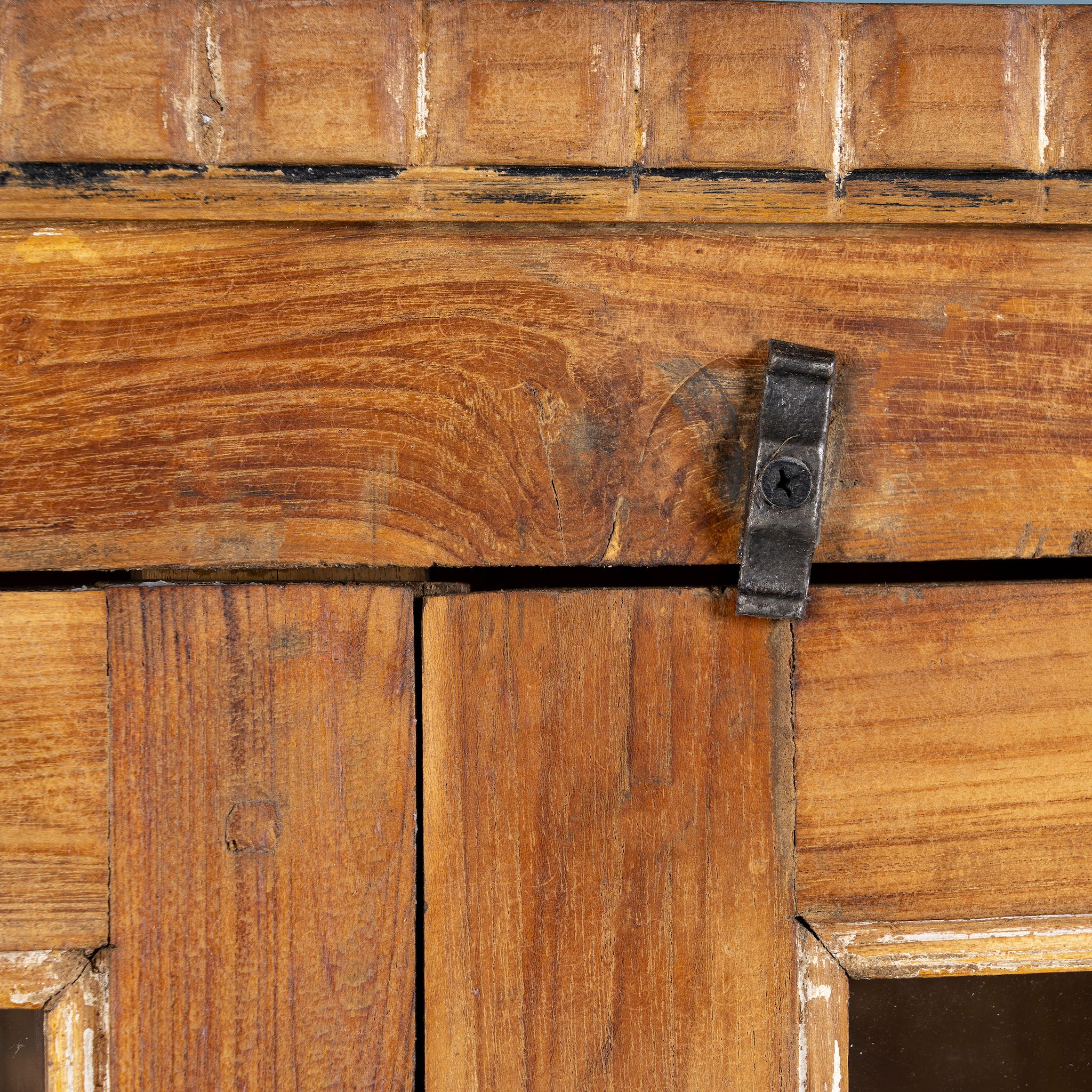 Close up image of a reclaimed teak wood display cabinet with four glass-panelled doors – wooden showcase cabinet crafted as sustainable furniture with timeless appeal.