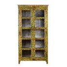 White background image of an and-painted floral showcase cabinet made from reclaimed wood with glass panelled doors and vintage rustic finish.