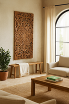Lifestyle scene with a hand-carved mango wood wall panel with intricate floral design and natural finish – Aruna model by Om Home & Garden