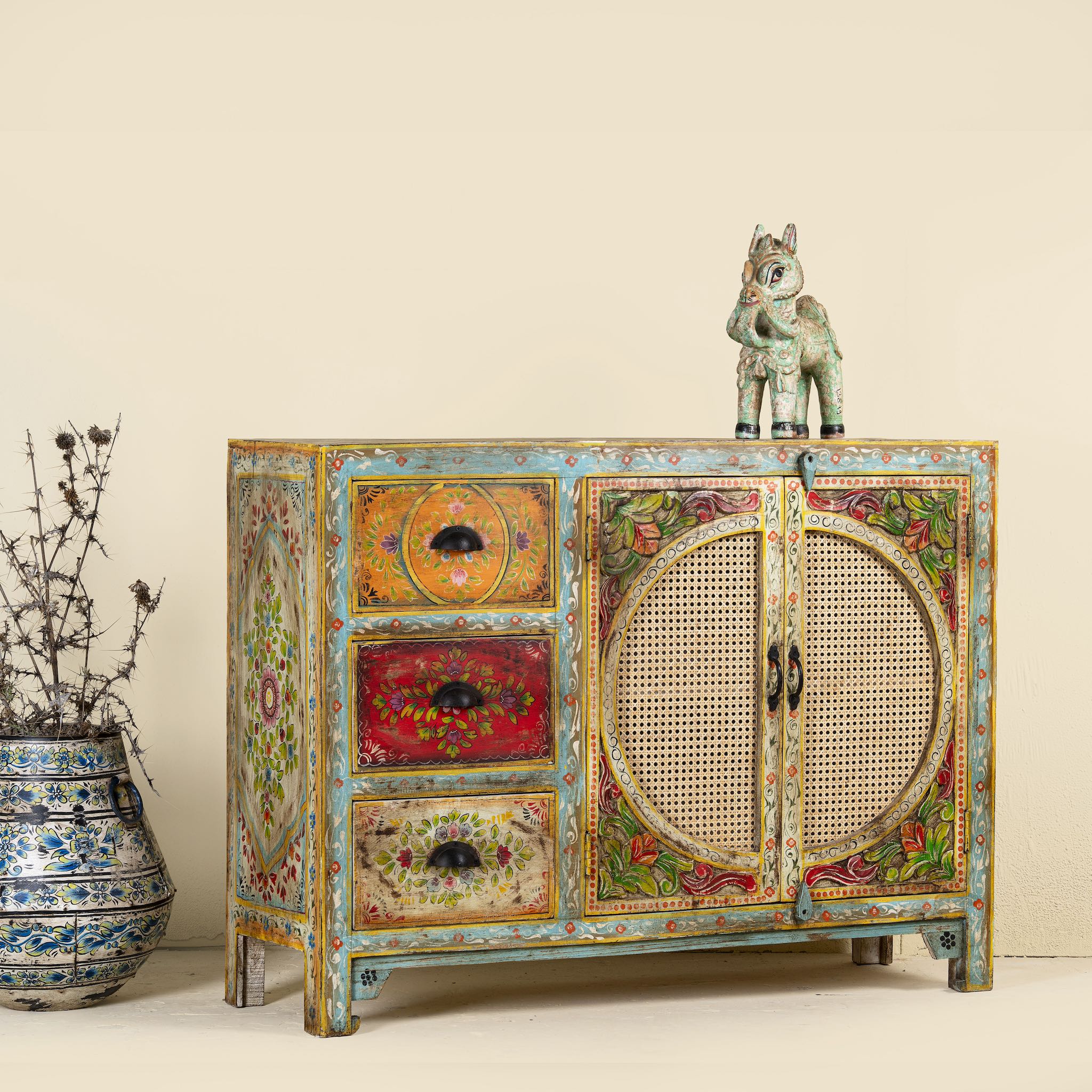 Side angle image of a hand painted sideboard Ashara made of mango wood with rattan inserts; Ibiza-inspired boho chic furniture, 120 × 40 × 92 cm.
