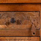 Close up image of a pair of mango wood night stands with floral hand carvings in natural wood colour.