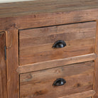 Close up image of a reclaimed wood sideboard Avika in a rustic minimalistic design with three drawers and two double-door cabinets. A sustainable furniture piece with warm wood tones and black iron handles, perfect for eco-conscious interiors.