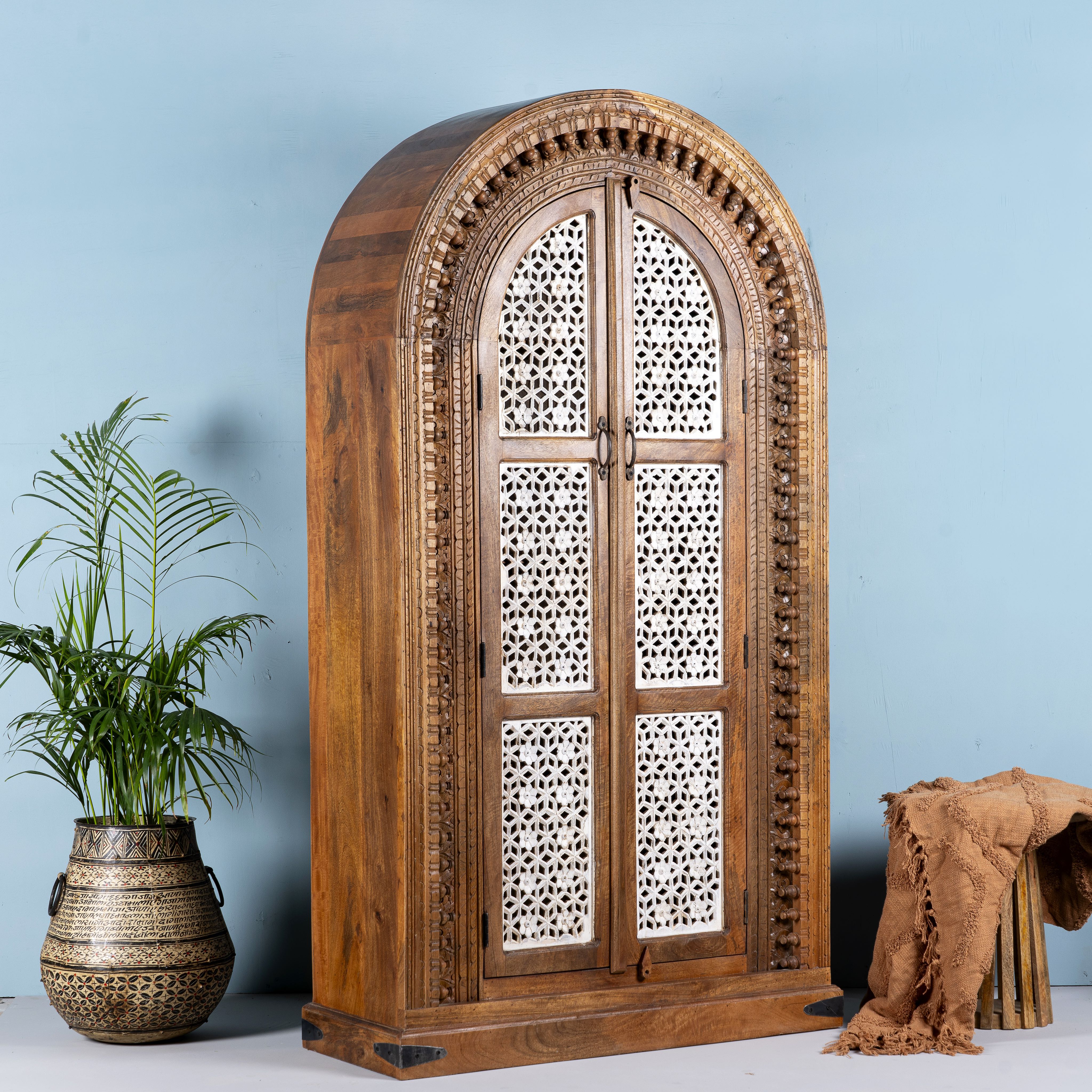 Side angle image of a handcrafted carved wooden wardrobe in half-round design with whitewashed lattice panels – bedroom furniture with Mediterranean flair and artistic detail.