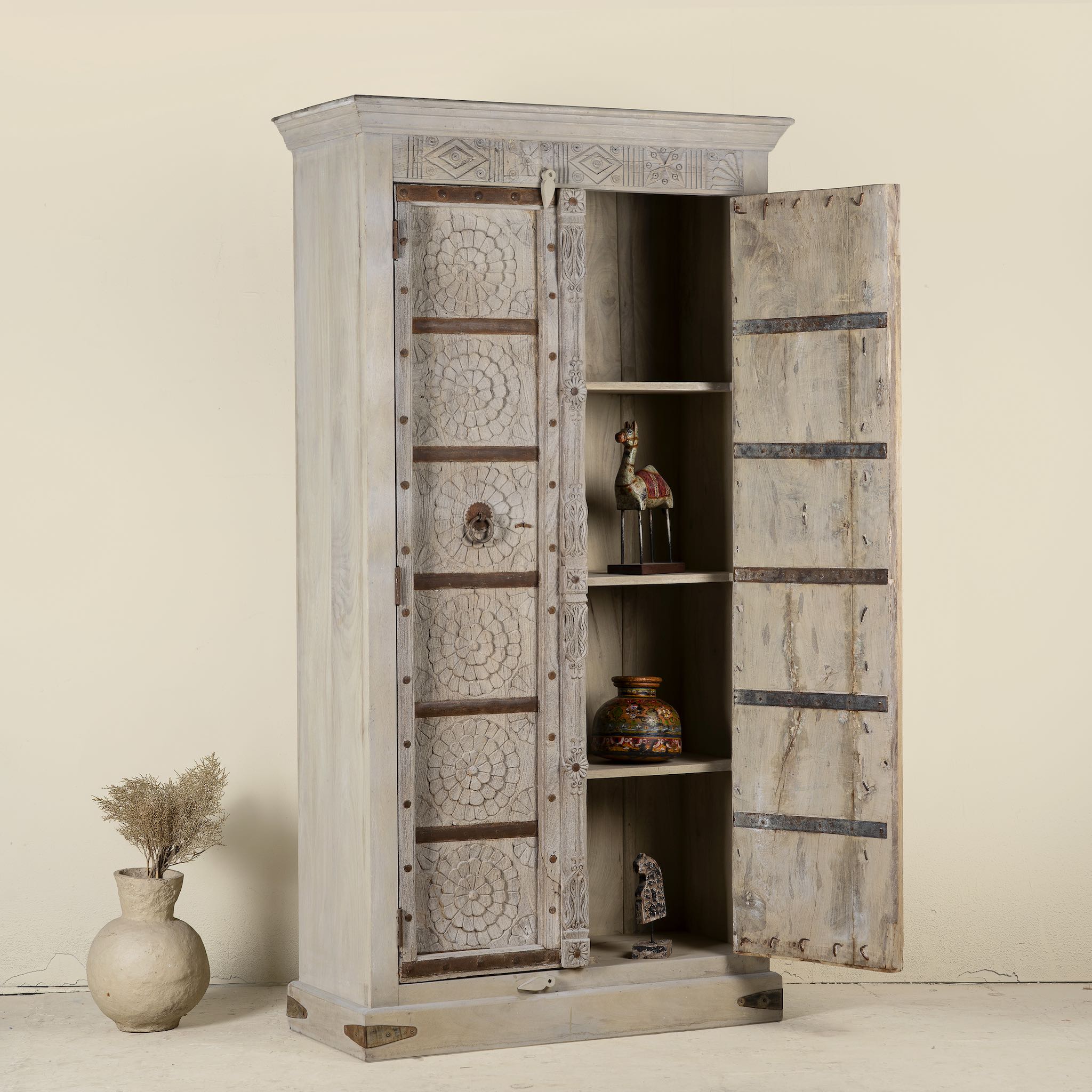 Wooden cabinet with open doors displaying decorative items on a neutral background