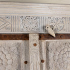 Close up image of a old door cabinet with reclaimed teak doors, floral carvings, and iron accents; artisan teak wood wardrobe with mango wood frame, 100 × 44 × 206 cm.
