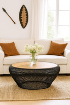 Lifestyle imagination of a large round metal base coffee table with recycled wooden top and woven iron base; minimalistic style coffee table, 100 cm diameter, 45 cm height.