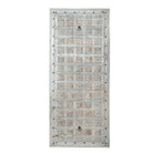 White background image of a Bansuri hand-carved teak headboard made from an old Indian ceiling door, featuring grid-style floral carvings and a distressed whitewashed finish—an eye-catching piece of old door headboards and old Indian door furniture.