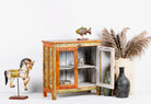 Side angle image with open door of a hand-painted teak wood display cabinet with glass doors and vibrant Indian motifs – sustainable furniture with vintage charm and artisanal detail.