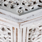 Close up image of a square mango wood coffee table with floral carvings and white wash finish; hand-carved and rustic, 90 × 90 × 46 cm.