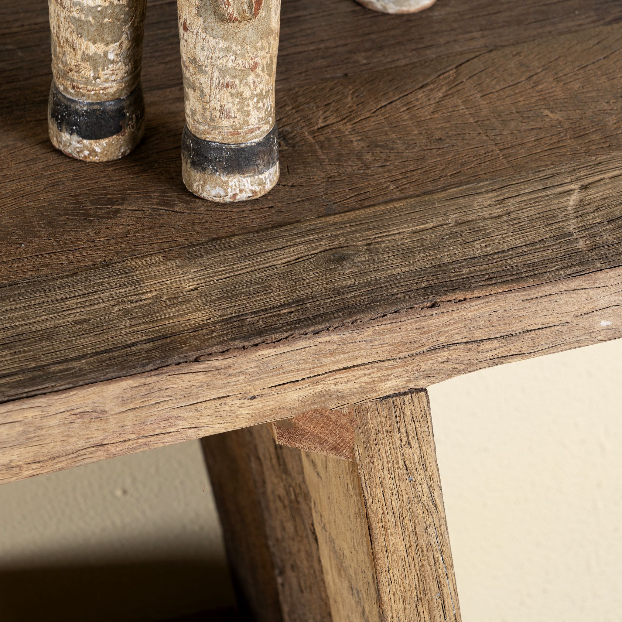 Close up image of a console table crafted from reclaimed teak wood, featuring a minimalist rustic design with angled legs and a lower shelf, showcasing the natural grain, texture, and character of the weathered wood.
