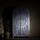 Lifestyle image of a Bhuvana arched mango wood wardrobe featuring a sculptural half-round design, intricate hand-carved floral detailing, and carved legs—an artisanal piece in the collection of arched wardrobes and mango wood wardrobes.