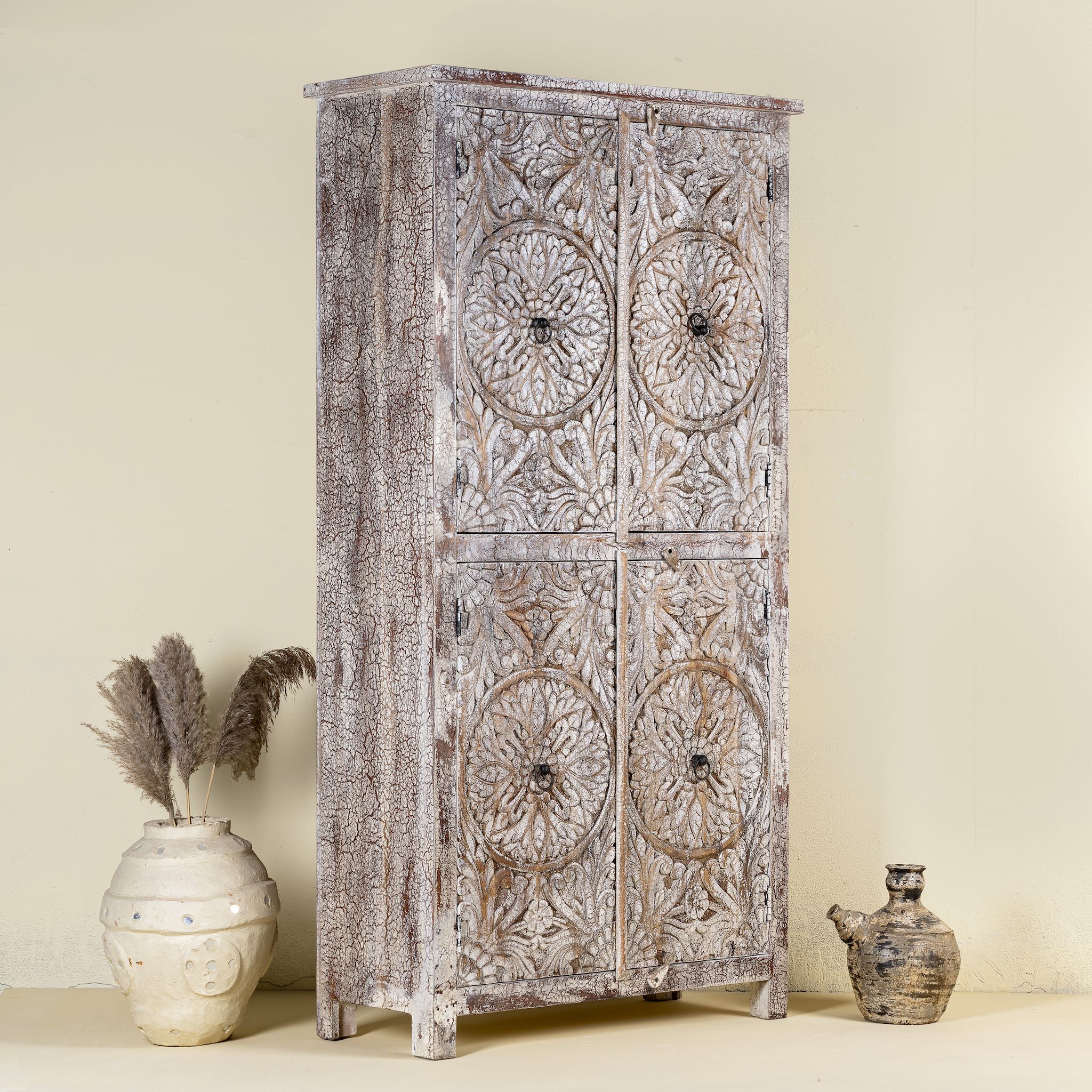 Side view of a hand carved acacia wood cabinet with floral design and 4 doors in a living room scene.