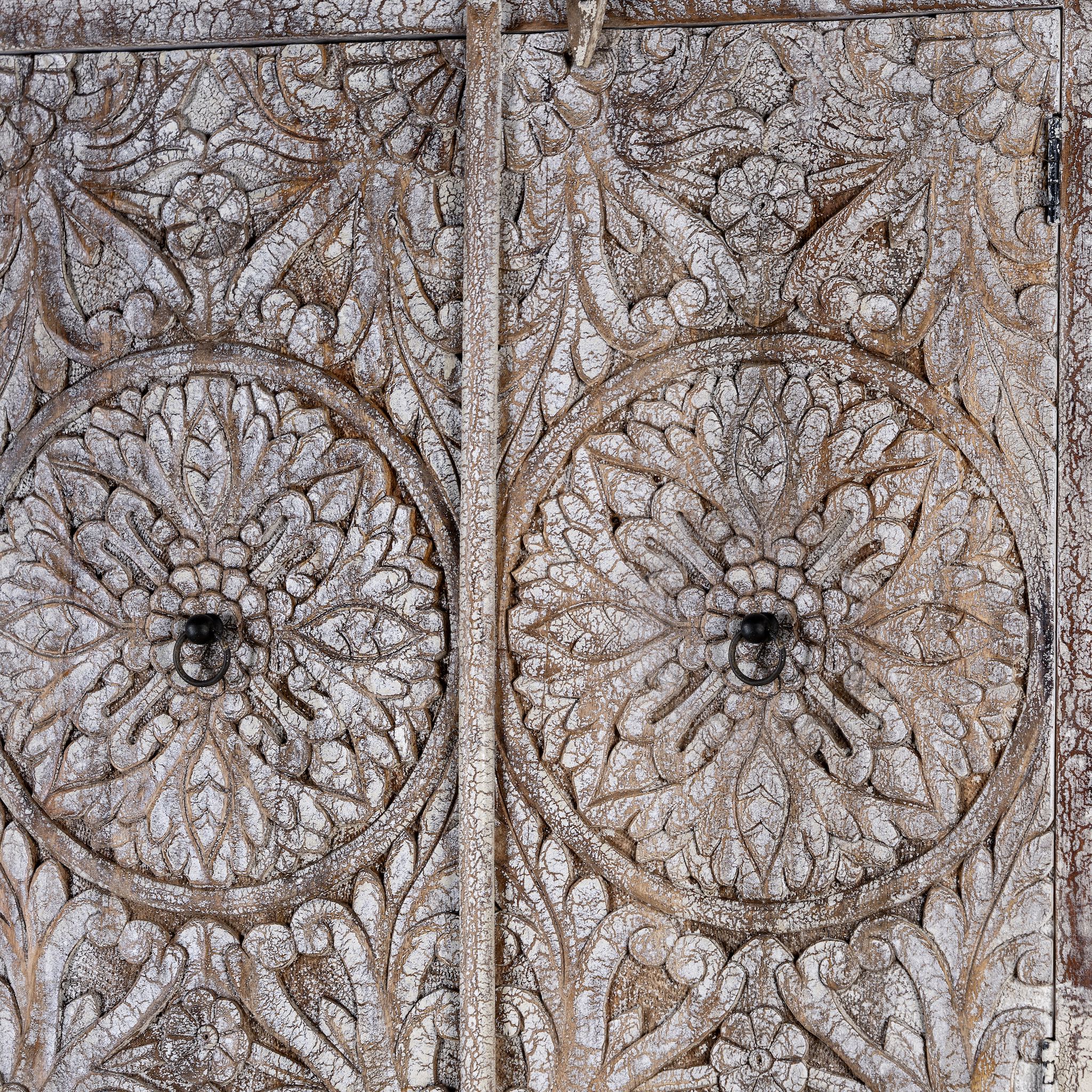 Close up picture of a hand carved acacia wood cabinet with floral design and 4 doors in a living room scene.
