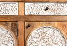 Close up image of a hand carved wooden sideboard made from mango wood with floral carvings and curved base, mango wood furniture with storage, 150 × 40 × 95 cm.