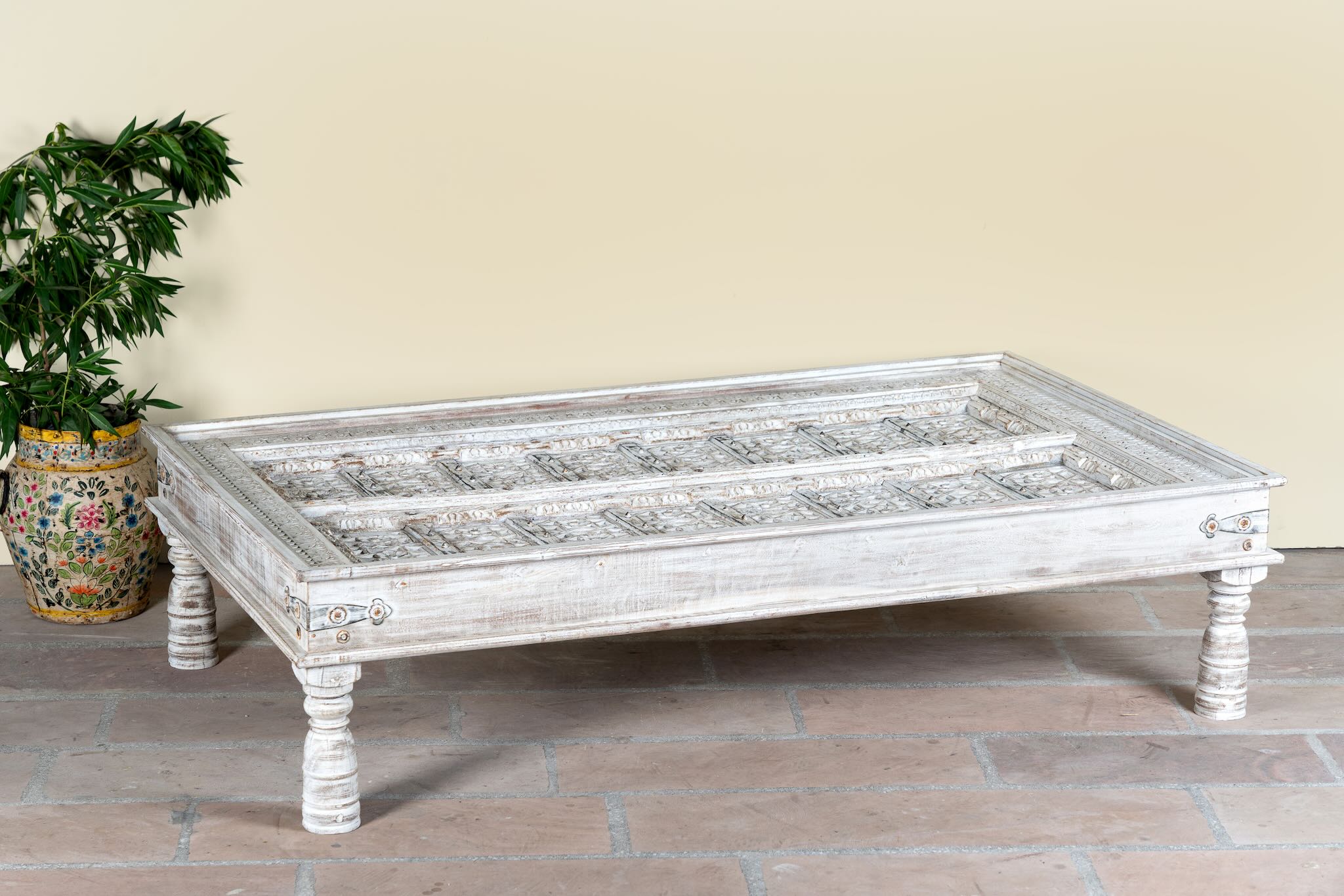 Lifestyle image of a white washed old door coffee table made of antique teak wood; handcrafted Indian coffee table, 185 × 109 × 46 cm.