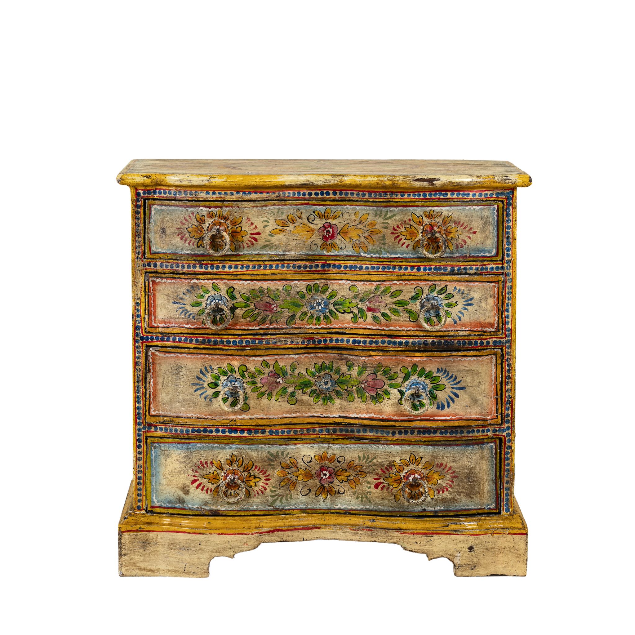 White background image of a hand-painted chest of drawers made from reclaimed wood, featuring a vibrant floral motif across its four drawers, with a distressed finish and colourful detailing that highlights its vintage, artisanal charm.
