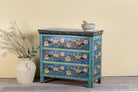 Side angle image of a hand-painted cupboard made of reclaimed wood with floral drawer fronts – Divisha model by Om Home & Garden