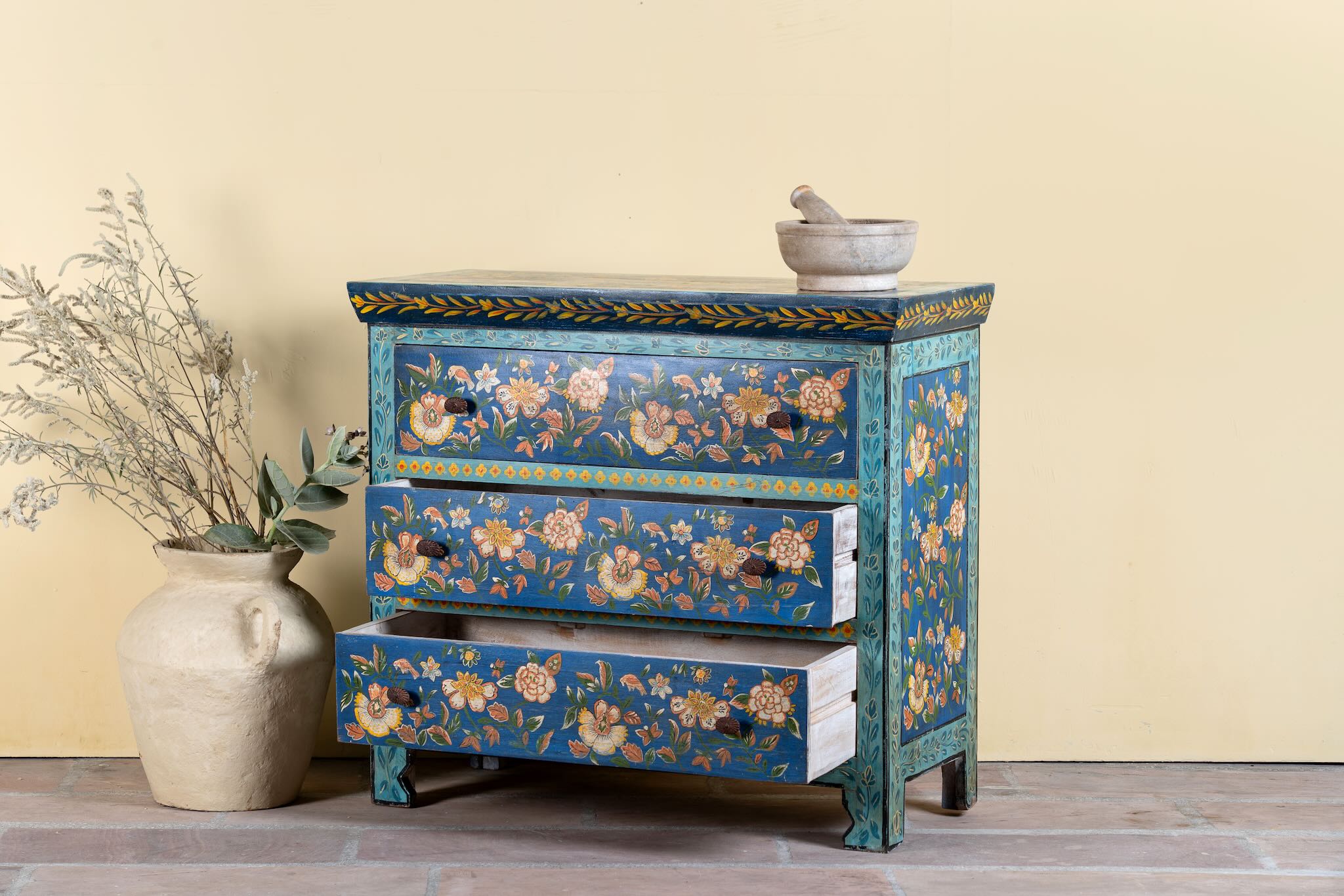 Side angle image with open drawers of a hand-painted cupboard made of reclaimed wood with floral drawer fronts – Divisha model by Om Home & Garden