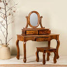 Side angle image of a handcrafted mango wood cosmetic table with a curved mirror and a matching chair.
