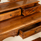 Close up image of a handcrafted mango wood cosmetic table with a curved mirror and a matching chair.