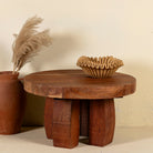 Front view of a wabi-sabi style rustic coffee table made of reclaimed wood in a living room scene in front of a light coloured wall.