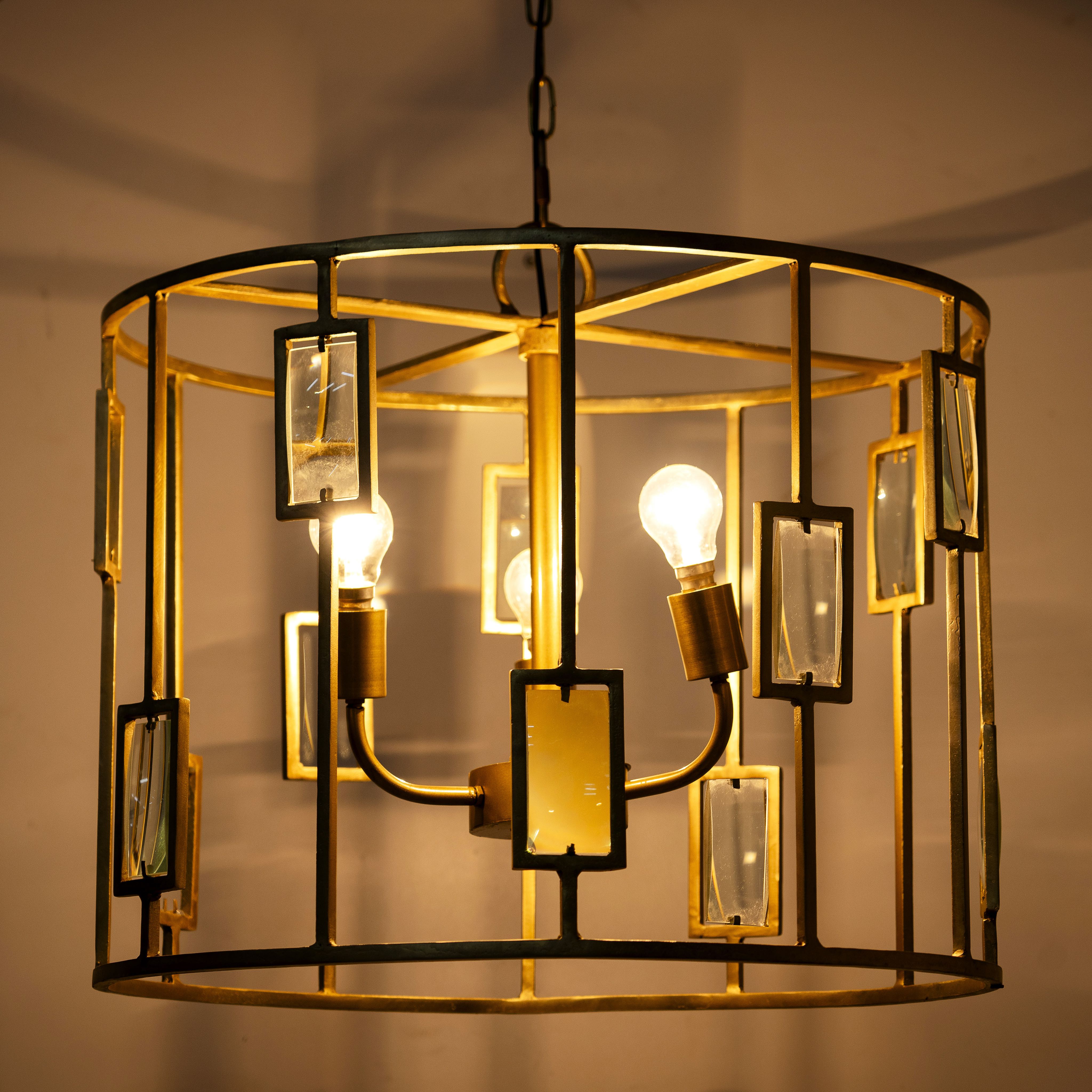 Image showing a lighted version of a unique pendant light with round shiny brass-plated frame and magnifying glass inserts – vintage lighting with three-light design for dining rooms, kitchens, or elegant interiors.