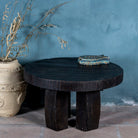 Front view of a rustic minimalistic style black coffee table made of reclaimed wood in a living room scene.