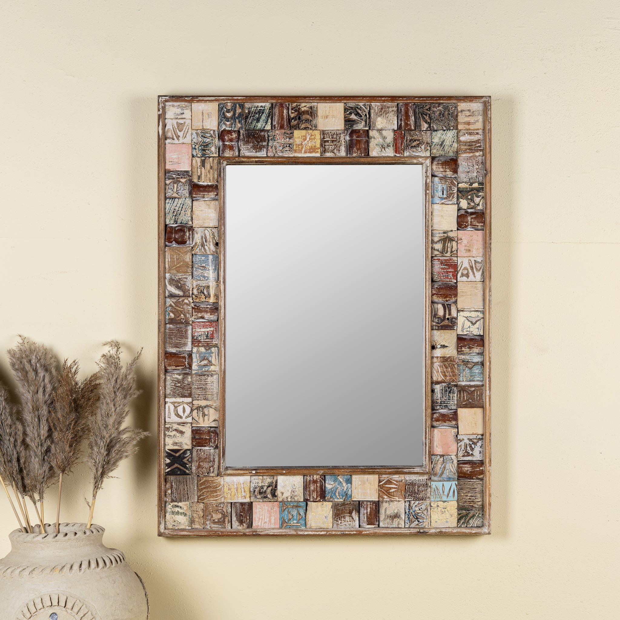 Front view image of a beautiful  Rectangular mirror framed with reclaimed wood, featuring a mosaic-style border of intricately carved and coloured wooden tiles, each with unique textures and patterns, creating a rustic and artistic statement piece.
