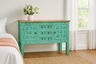 Lifestyle imagination of a green storage console table with carved mango wood doors and brass details; mango wood console table, 130 × 100 × 40 cm.