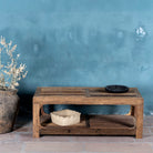 Front view of a coffee table made of reclaimed wood in Wabi Sabi style decorated in a living room scene.