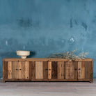 Lifestyle image of a sustainable driftwood furniture lowboard made from reclaimed wood with four cabinets and rustic finish; 230 × 45 × 60 cm.